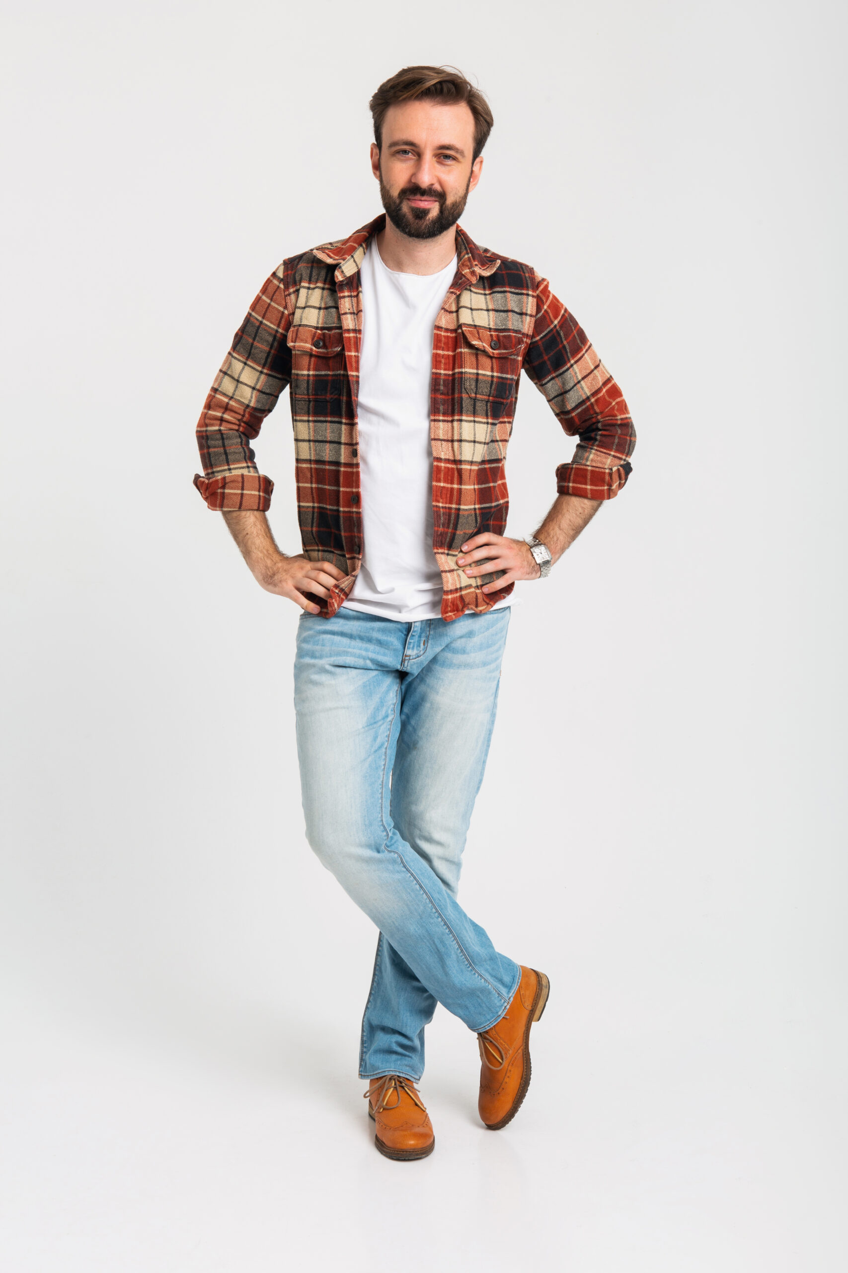 isolated handsome bearded man in hipster outfit dressed in jeans and checkered shirt full length standing on white studio background, attractive guy