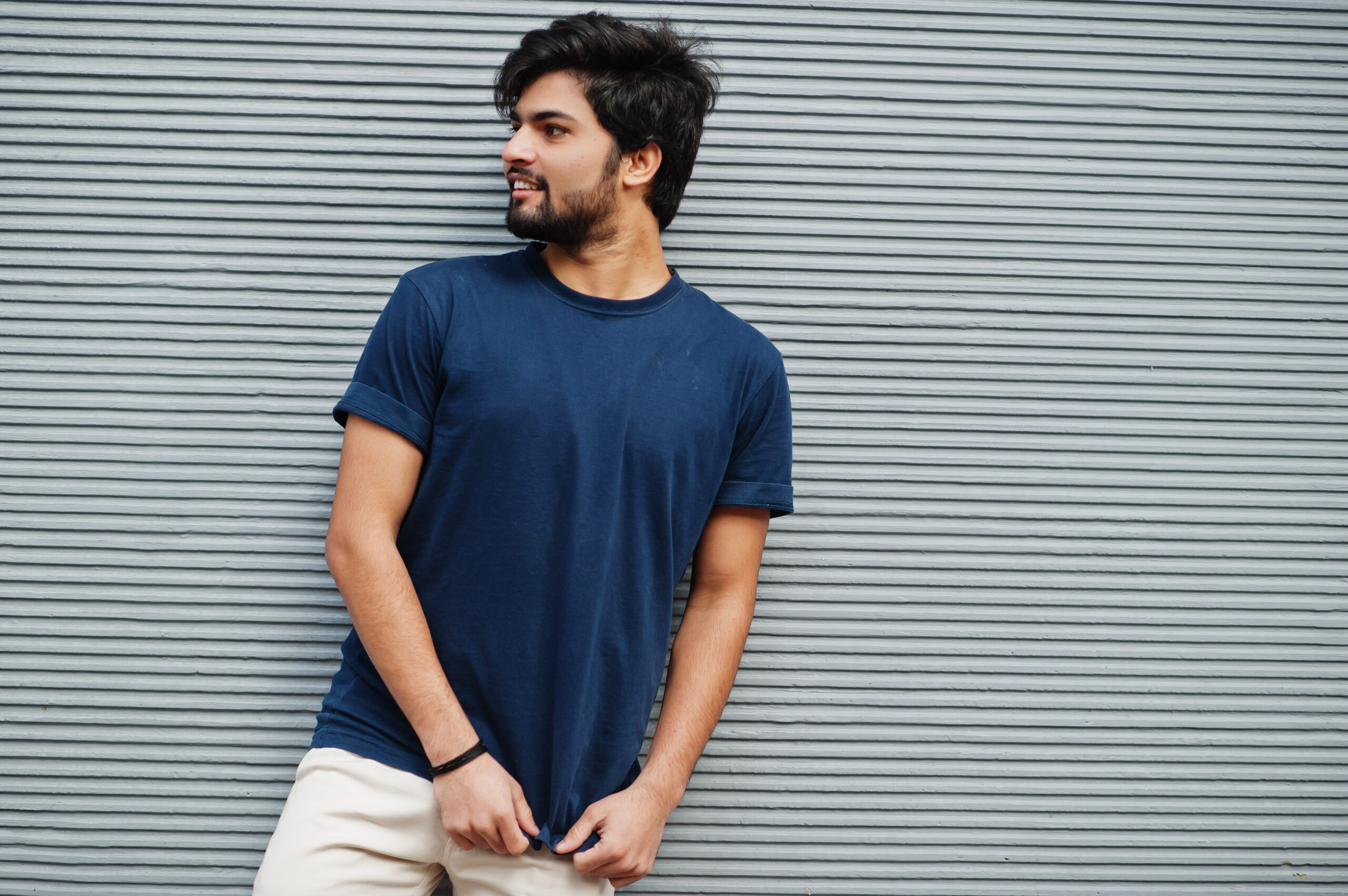 Stylish casual indian man wear blue t-shirt posing against grey